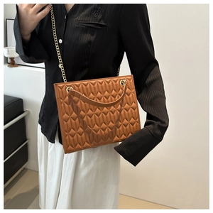 Detailed view of a brown quilted chain bag worn by a model in a modern setting