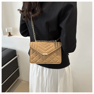 Close-up of beige quilted chain shoulder bag with V-shaped stitching and golden metal clasp
