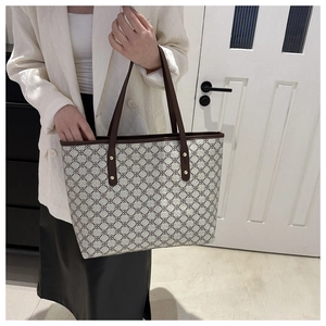 Detail of vintage monogram pattern on tote bag with leather straps and gold rivets