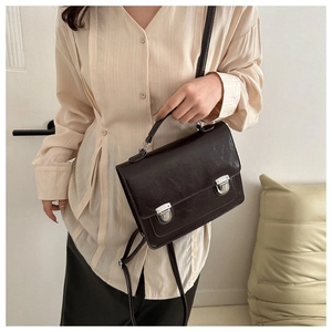 Sac vintage marron foncé avec deux fermoirs argentés porté par un mannequin