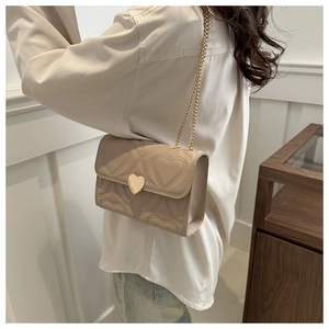 Détail du sac beige matelassé cœur avec fermoir doré en forme de cœur et bandoulière