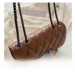 Detail of brown quilted leather texture and dark metal chain on a retro crossbody bag