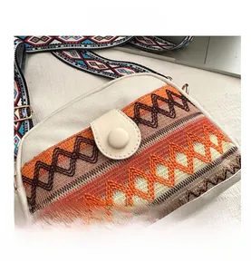Gros plan sur la broderie géométrique du sac ethnique en toile avec bandoulière large