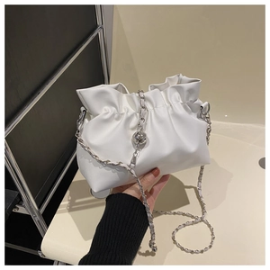 Detail of white pleated cloud bag with elegant silver chain and metal ball ornament