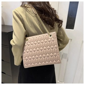 Detailed back view showing the size and fit of the beige quilted chain shoulder bag on a model