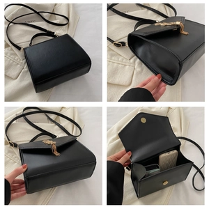 Detail view of black vintage crossbody bag showing magnetic closure and gold tassel hardware