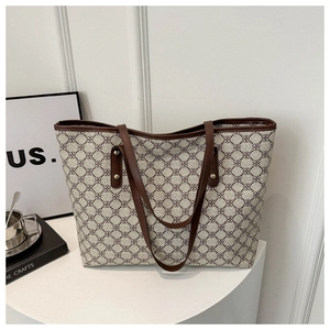 Detail of vintage patterned tote bag with brown leather trim and gold rivet accents