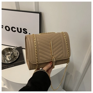 Close-up of khaki quilted leather crossbody bag with gold tassel hardware and chain strap