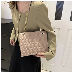 Chic quilted beige shoulder bag with gold chain strap styled on a green blazer