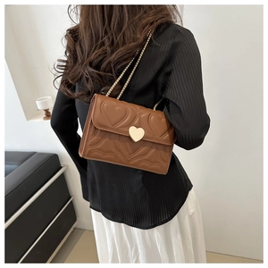Sac bandoulière en cuir marron avec matelassage cœur et chaîne dorée sur un mannequin