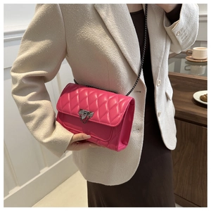 Close-up of fuchsia quilted crossbody bag with metal chain strap and decorative lock