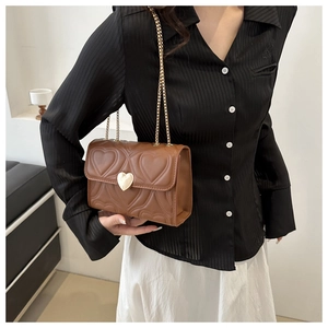 Détail du sac en cuir marron matelassé en cœur avec fermoir doré et bandoulière chaîne