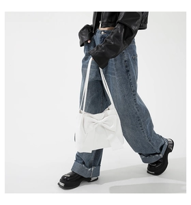 Detail of white bow tote bag with smooth faux leather texture held by a model