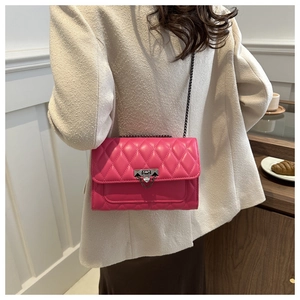 Detail of the elegant fuchsia quilted crossbody bag with a silver triangle metal lock closure