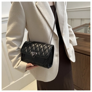 Detail of black quilted leather shoulder bag with dark grey metal chain and lock