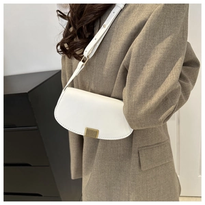 Detailed shot of a white saddle bag with a golden metal buckle and fine stitching