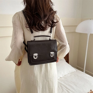 Sac à dos rétro marron foncé avec boucles argentées dans un intérieur minimaliste