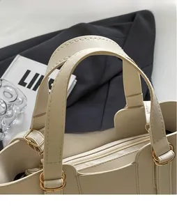 Detail of beige PU leather handbag showing top handle, gold hardware and zipper closure