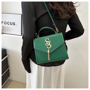 Detail of dark green leather handbag featuring gold S-logo hardware and elegant tassel