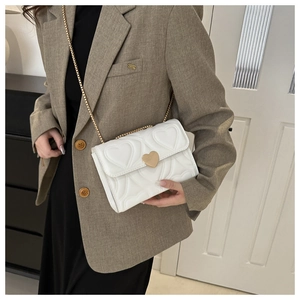 Détail du sac blanc matelassé en cuir PU avec chaîne dorée et fermoir pivotant en cœur