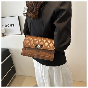 Close-up of brown quilted crossbody bag with metal chain strap and turn-lock closure