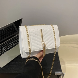 White quilted crossbody bag with gold chain strap and tassel detail in lifestyle setting