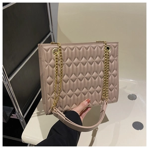 Detail of beige quilted tote bag featuring diamond stitching and gold chain strap