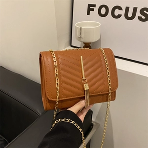 Caramel brown quilted chain crossbody bag with V-shaped stitching and gold tassel detail