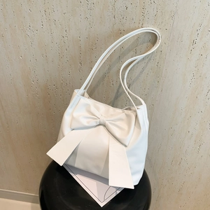 White minimalist tote bag with a large bow detail on a black stool indoor setting