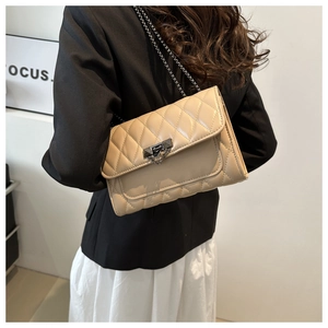 Detail of beige quilted leather handbag with triangular metal clasp and fine chain strap