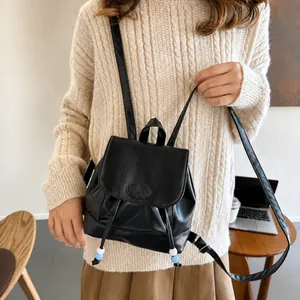 Detalle de mini mochila de cuero PU negro con cordón ajustable decorado con cuentas bicolores