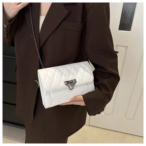 Close-up of white quilted PU leather crossbody bag with dark grey metal chain and buckle