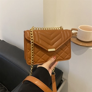 Brown quilted PU leather crossbody bag with gold chain strap in a stylish indoor setting