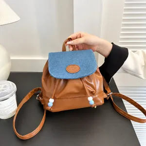 Detalle de mini mochila bicolor con diseño de patchwork vaquero y cierre de cordón