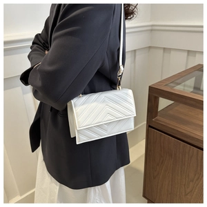 Détail du sac bandoulière blanc avec surpiqûres en chevron et sangle en cuir élégante