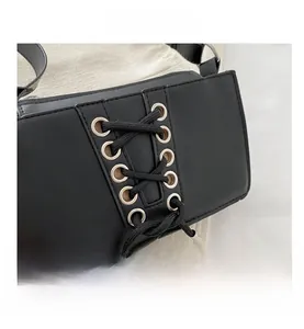 Détail du sac à bandoulière noir en similicuir avec ruban entrelacé et œillets métalliques