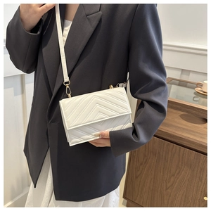 Détail d'un sac bandoulière blanc en similicuir matelassé avec finitions dorées