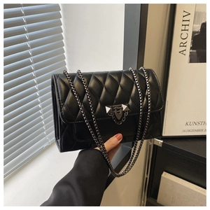 Close-up of black quilted PU leather shoulder bag with metallic chain and rivet detail