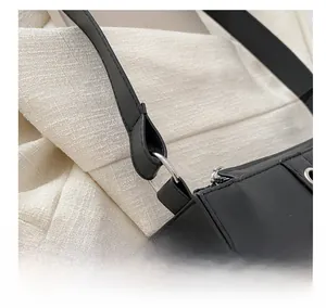 Gros plan détaillé de l'anneau métallique argenté sur un sac à bandoulière en cuir noir