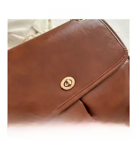 Close-up of brown textured leather flap bag with a golden turn-lock metal clasp
