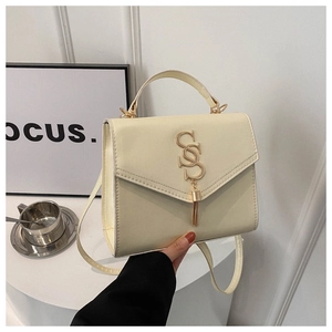 Macro shot of cream faux leather bag texture with golden logo and tassel detail