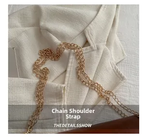 Detailed close-up of the polished gold metal chain strap on a stylish shoulder bag