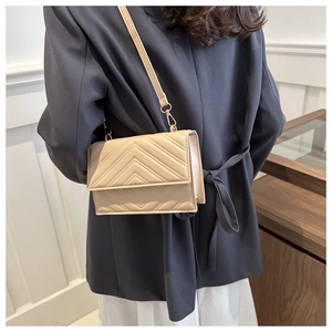 Détail du sac bandoulière beige avec surpiqûres en V élégantes et ferrures dorées