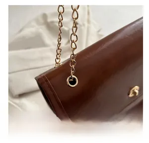 Macro view of gold chain link hardware and brown leather stitching on shoulder bag