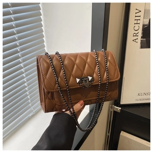 Close-up of brown quilted leather texture and pyramid stud buckle on chain bag