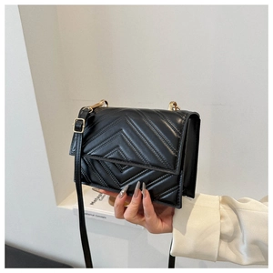 Détail d'un sac bandoulière en cuir matelassé noir avec coutures en V et boucle dorée