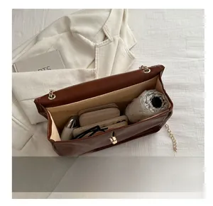 Top view of spacious brown leather shoulder bag interior holding an umbrella and phone