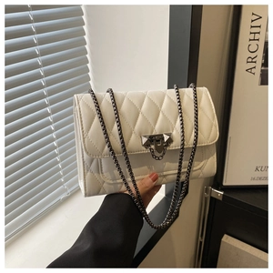 Detail of white quilted leather texture and dark gray metal chain strap on a tote bag
