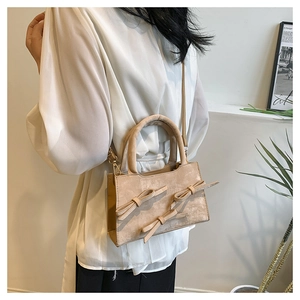 Détail d'un sac à main beige en PU avec trois nœuds décoratifs porté par un mannequin à l'épaule