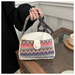 Macro detail of ethnic canvas bag showing colorful woven patterns and broad shoulder strap